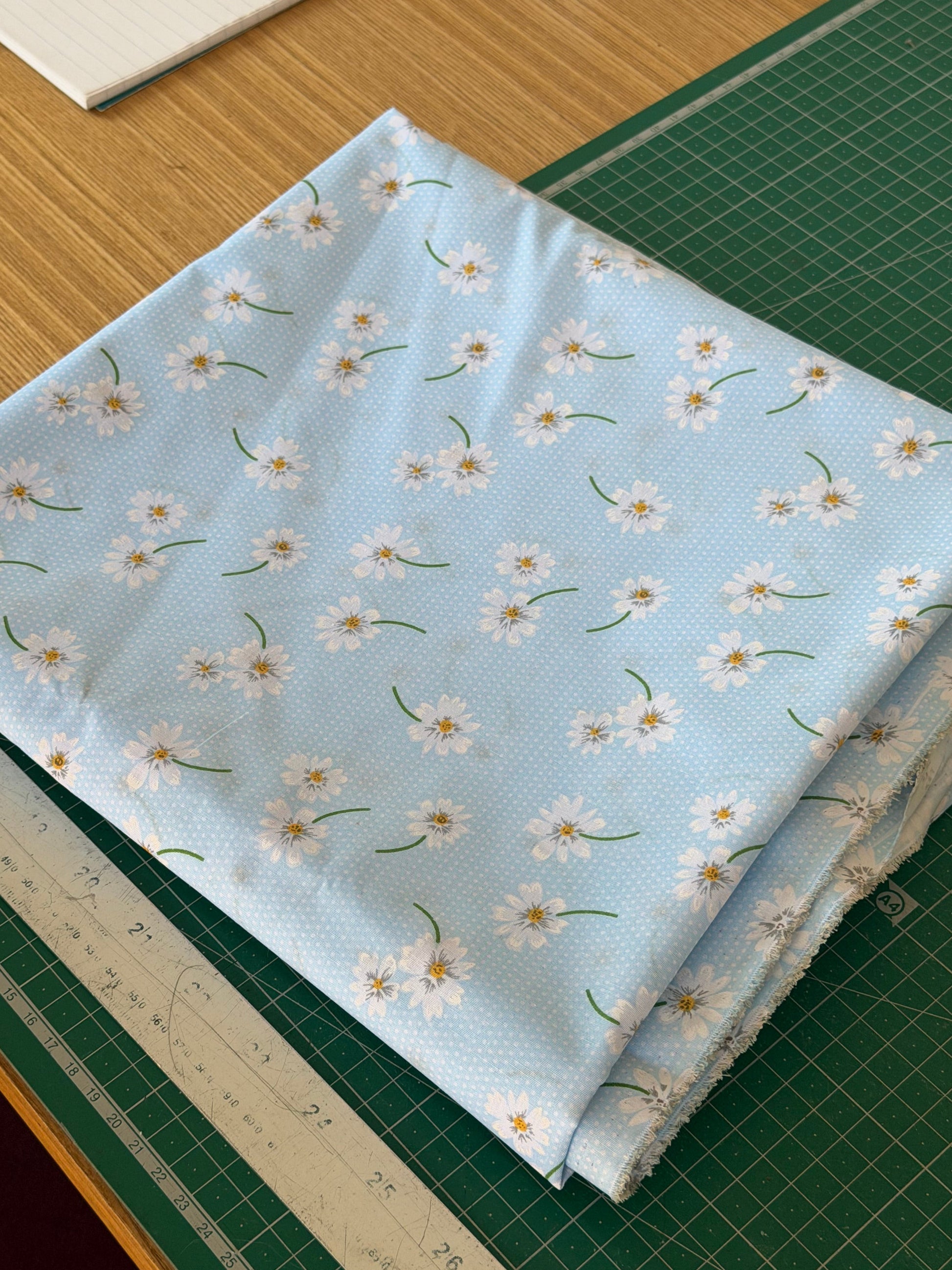 Light blue fabric with floral pattern on a cutting mat