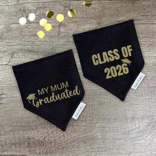 Two black graduation bandannas with gold text reading 'my mum graduated' and 'class of 2026' on a wooden surface with confetti.